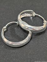 pair of silver hoop earrings on black background