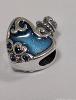 Front view of sterling silver heart bead with blue enamel and scroll detail