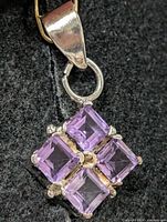 Front view of silver pendant showing four square amethysts