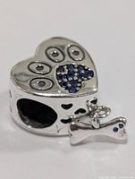 Front view of silver heart charm bead with blue pavé paw print and bone dangle