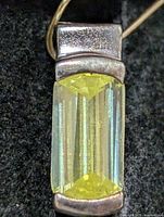 Front close-up of silver pendant showing yellow CZ stone and metal setting
