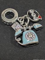 Front view of sterling silver bead charm showing rotary phone, speech bubble dangles and pavé carrier