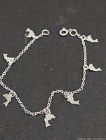 Overall view of the silver bracelet showing chain and dolphin charms