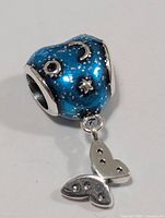 Front view of blue enamel heart-shape bead with silver celestial motifs and heart dangle