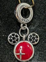 Front view of silver pendant showing red enamel center, black stone ears, S925 stamped bail