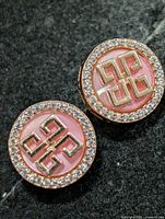 Front view of both earrings showing pink center, geometric motif, CZ halo