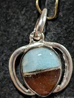 front view of silver pendant showing larimar and amber cabochon