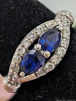 Top view of silver ring showing marquise created sapphires and CZ halo