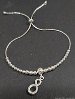 Full view of silver bolo bracelet showing beads, slider clasp and infinity charm