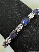 Close view front of ring showing alternating marquise blue sapphires and round clear stones