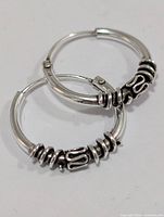 Both silver hoop earrings showing decorative bead details
