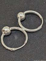 Front view of both silver hoop earrings on dark background