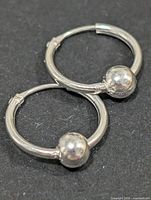 Close-up of both silver hoop earrings showing bead accents