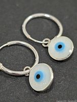 pair of silver hoop earrings with evil eye charms