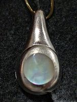 Front view of silver-tone drop pendant showing mother of pearl cabochon