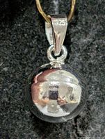 Front view of polished sterling silver ball pendant showing reflective surface and bail