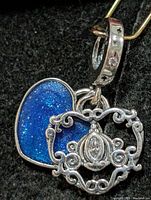 Front view showing blue glitter heart, openwork filigree charm, star-engraved bail