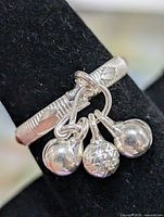 Front view of ring on display showing charms and band engraving