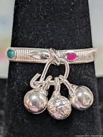 Front view of silver-tone ring showing ball charms and inlay accents