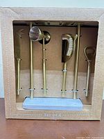 Front of boxed Mason Grove bar tool kit showing four gold tools on marble stand