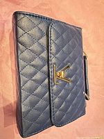 Front view of navy quilted handbag showing gold-tone turn lock clasp
