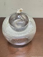 Front view showing spherical clear glass lamp, bubble pattern, cotton wick