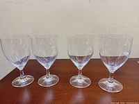 Full view of four matching clear wine glasses
