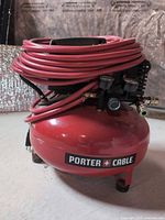 Full view of Porter Cable pancake air compressor with coiled red hose attached