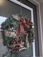 Full view of artificial evergreen wreath hanging on door