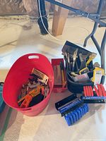 Overall view of red tub, black bin, hex key sets on floor