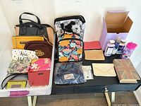 Assorted handbags, pouches, backpacks, body care set, water bottle and decorative book box displayed on table