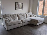 Full view of beige woven fabric sectional sofa in room