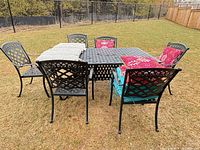 Full view of rectangular cast aluminum table with six matching chairs, turquoise seat cushions, pink pillows