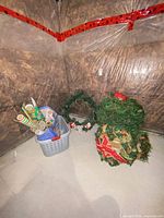 Overview of wreaths, basket with wrapping paper and décor on basement floor