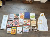Overview of all cookbooks, apron, menu sign and metal trivets