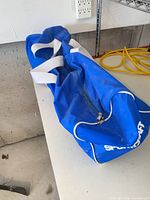 Blue Sportcraft duffel bag closed on table, shows dirt