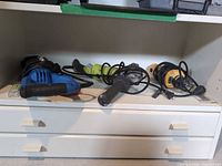 Shelf with three corded power tools: Mastercraft reciprocating saw, Ryobi AG453G grinder, DeWalt DW660 cut-out tool
