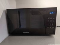 Front view of Frigidaire black countertop microwave with LED display lit