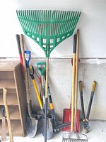 Group of long-handle garden tools leaning against wall