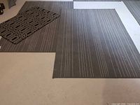 Two grey striped rugs and one smaller black geometric rug on floor