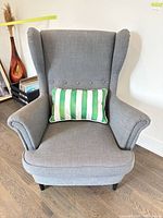 Front view of gray wingback chair with striped pillow