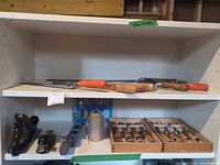 Shelf showing panel saw, coping saw, planes, chisels in boxes, packaged blades