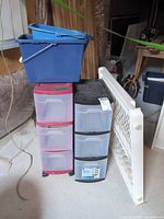 Overall lot showing mop bucket, two drawer towers, gate, step stool