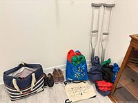 Overall lot showing striped tote, two pairs shoes, reusable bags, crutches