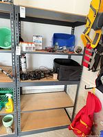 Full view of gray steel shelving unit with three MDF shelves, assorted contents shown but excluded