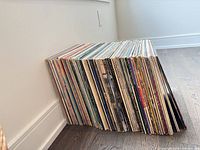 Stack of roughly 40 LPs leaned against wall