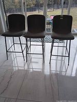 Front view of the three gray fabric bar stools