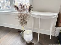 console table, lamp base with shade, vase with peacock feathers