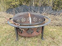 Side view of rusted steel fire pit with guard ring, spark screen and poker