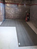Three grey striped rugs laid side by side in basement